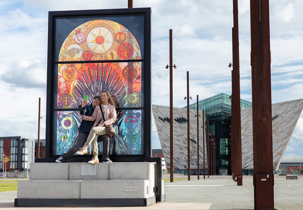 Reconnect in Ireland - Image here shows a couple taking a selfie while sitting in front of "Glass of thrones" outside of Titanic Belfast, County Belfast.