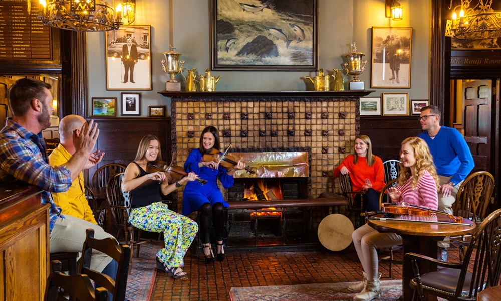 Reconnect in Ireland - Image shows a group of people listing to two female fiddlers in the pub/bar at Balinahinch Castle, County Galway. 