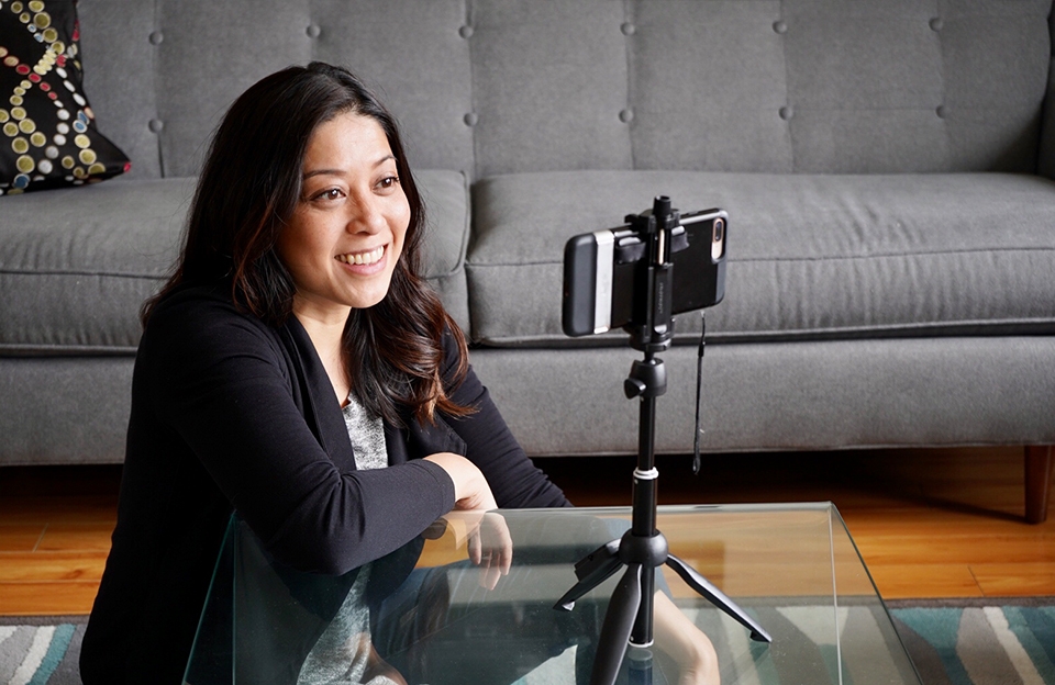 Image of Donna Santos using mini tripod to hold smartphone at eye level for virtual meeting. Photo courtesy of Donna Santos Photography.