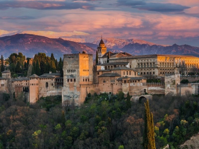 Spain has 47 properties on the UNESCO World Heritage List. Image here shows the exterior of the Alhambra Palace in Granada with the Sierra Nevada mountains in the background. Photo by Marcin Jucha | Canva.